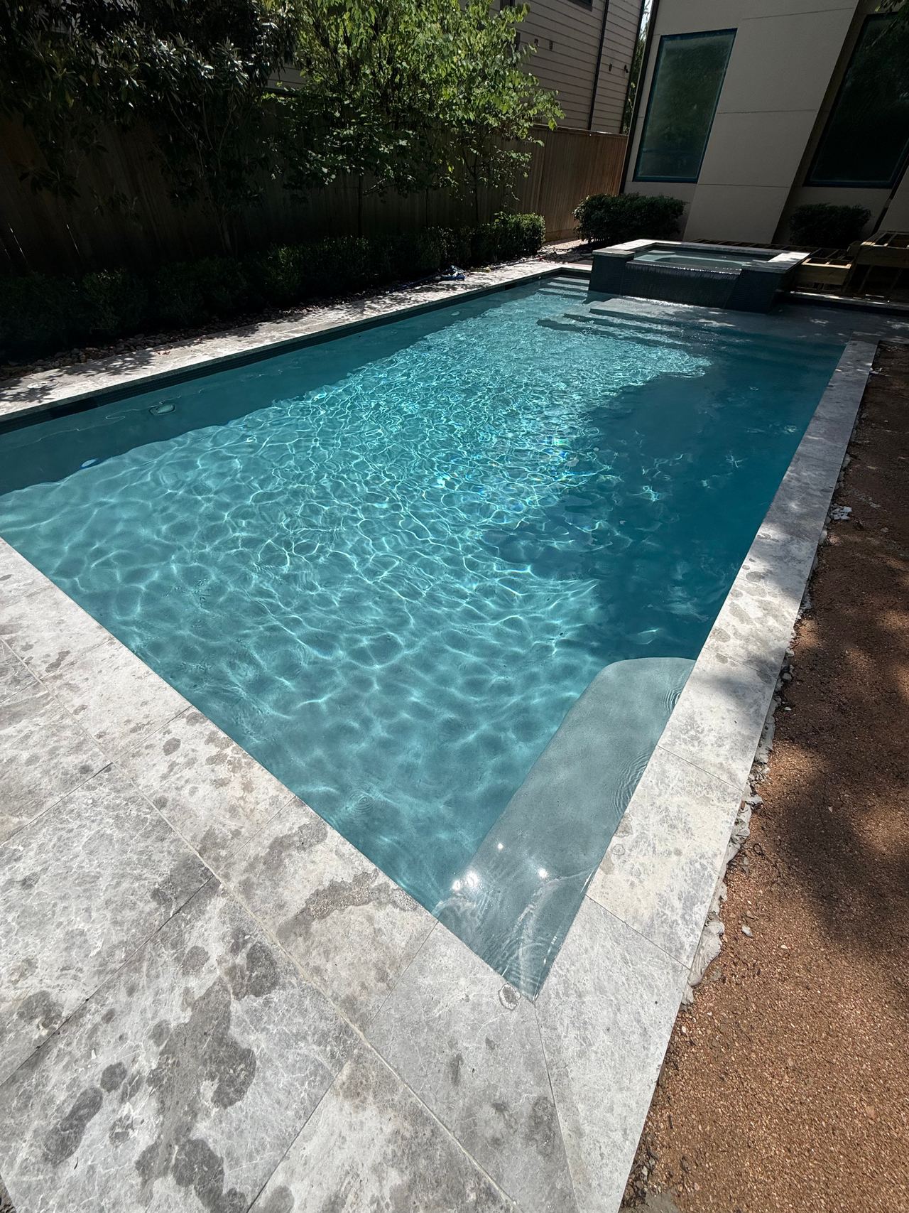 Rectangular pool with clear turquoise water, a raised spa at the far end and grey stone coping, after a Happy Frog Pools clean