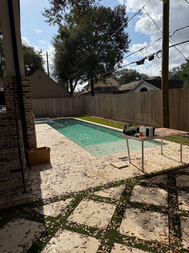 Before: the long pool seen from the patio, with green-tinted water, leaves all over the deck and a work table of supplies