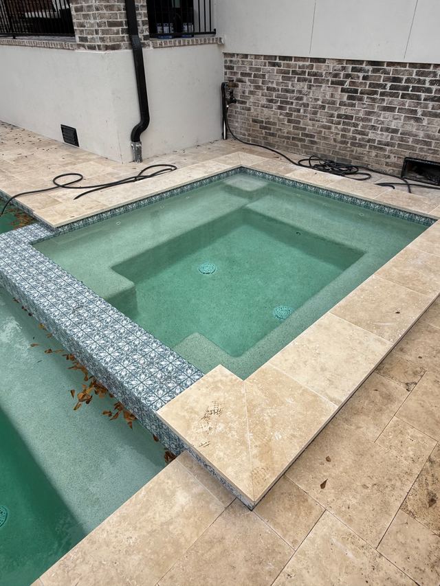 Before: square spa with green-tinted water and leaves on the edge